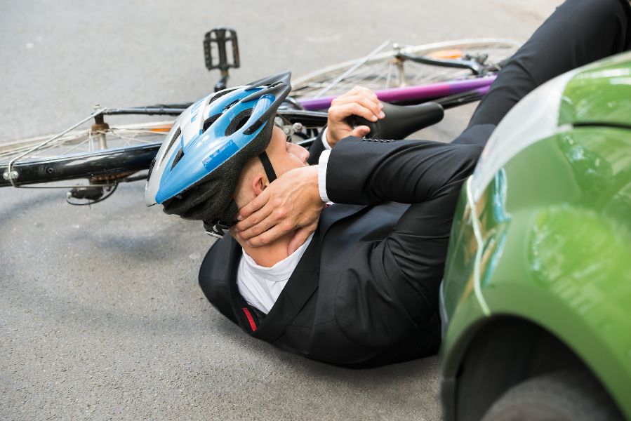 An injured man, lying on the ground after being knocked off his bicycle by a car driver